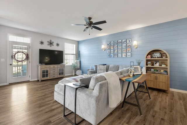 living area featuring wood finished floors, baseboards, and ceiling fan