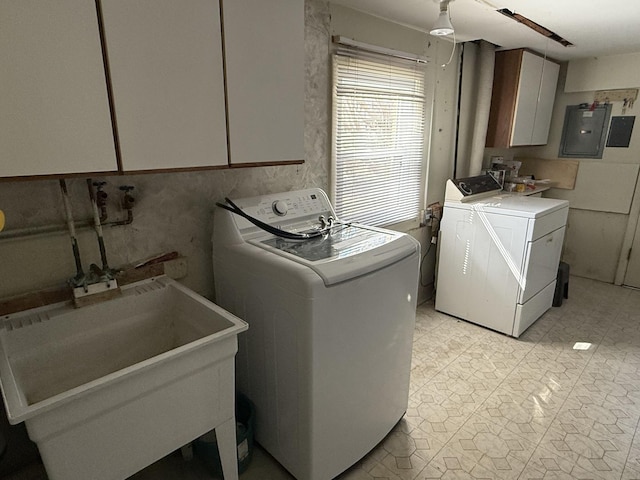 laundry room with light floors, washing machine and clothes dryer, electric panel, cabinet space, and a sink