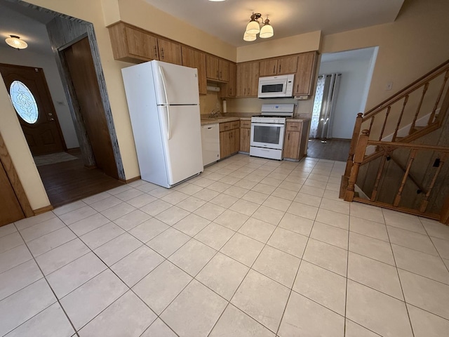 kitchen featuring white appliances, light tile patterned flooring, plenty of natural light, a sink, and light countertops