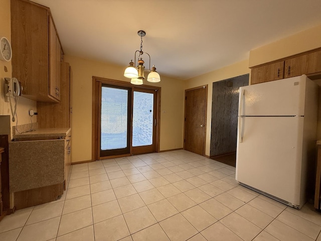 kitchen with an inviting chandelier, light tile patterned floors, brown cabinets, and freestanding refrigerator