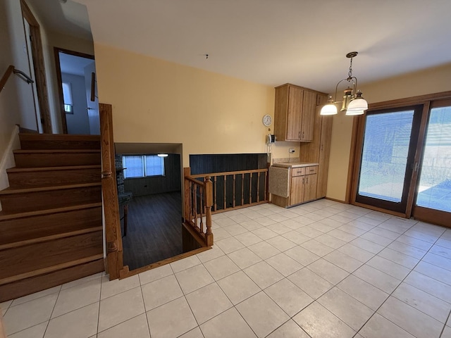 kitchen with a chandelier, light countertops, hanging light fixtures, brown cabinets, and light tile patterned flooring