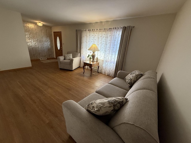 living room with wood finished floors, visible vents, and baseboards