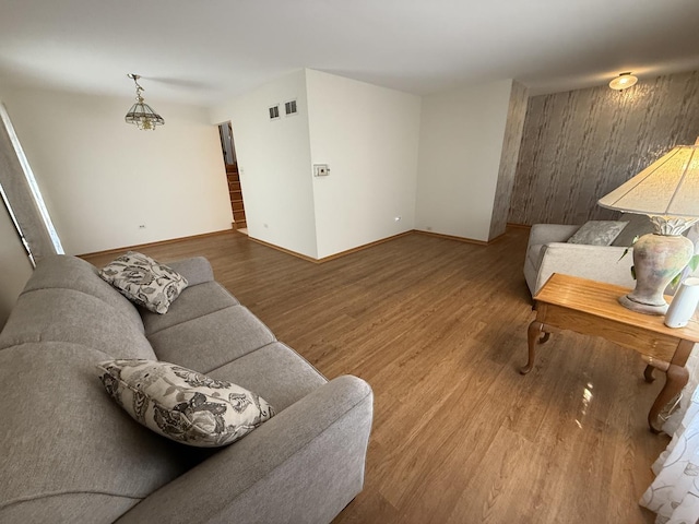 living room featuring visible vents, baseboards, and wood finished floors