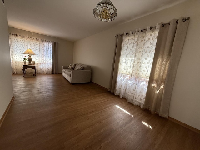 unfurnished room featuring baseboards, an inviting chandelier, and wood finished floors