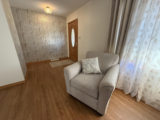 sitting room with visible vents, baseboards, and wood finished floors