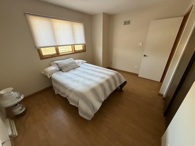 bedroom featuring visible vents, baseboards, and wood finished floors