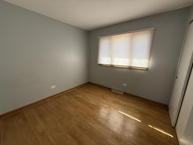 empty room with visible vents, baseboards, and wood finished floors