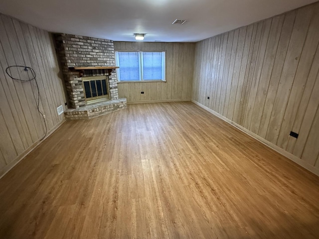 unfurnished living room featuring visible vents, baseboards, a brick fireplace, and wood finished floors