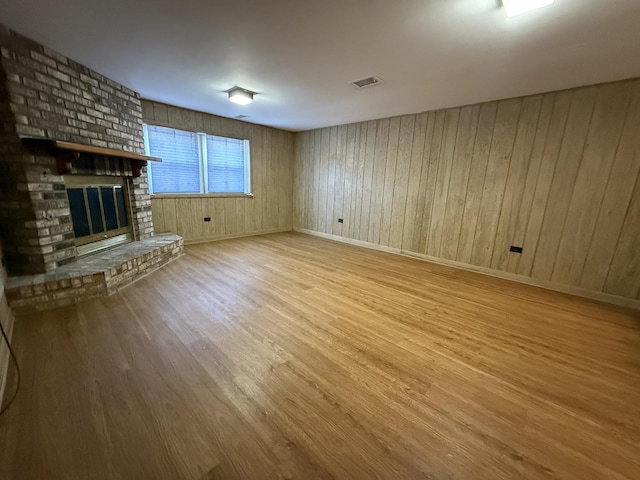 unfurnished living room with visible vents, baseboards, wood finished floors, and a fireplace