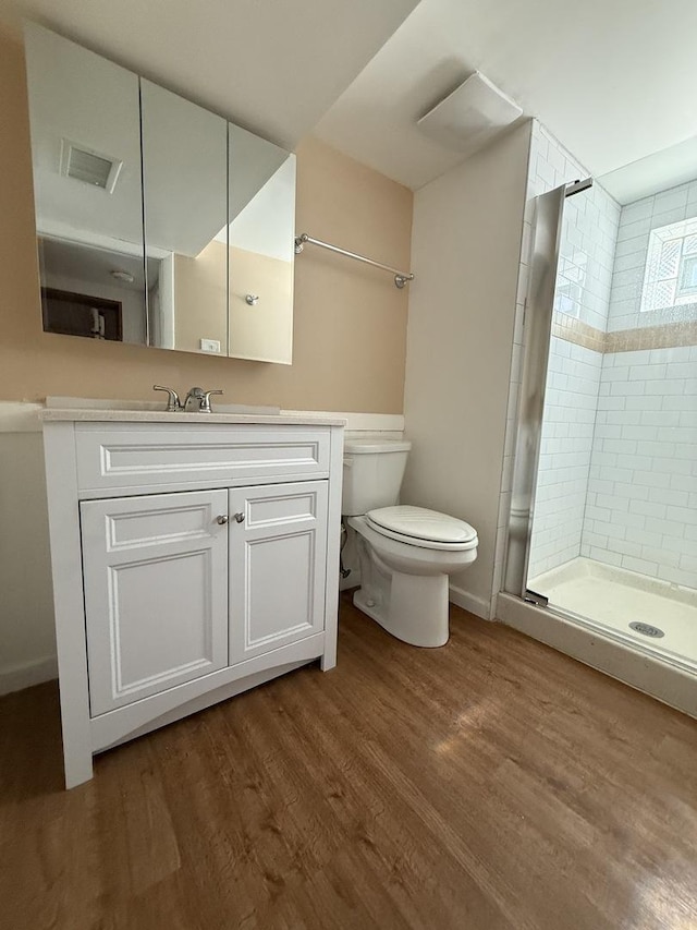 bathroom with visible vents, a shower stall, toilet, wood finished floors, and vanity