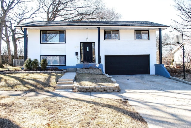 split foyer home featuring brick siding, a garage, and driveway