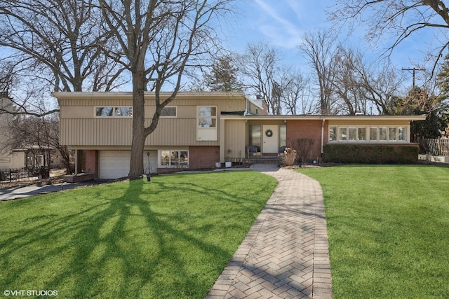 tri-level home featuring a front lawn, brick siding, and an attached garage