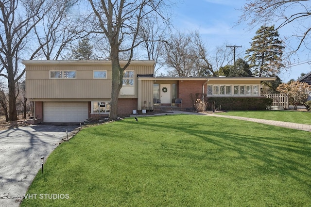 split level home with driveway, a front lawn, brick siding, and an attached garage