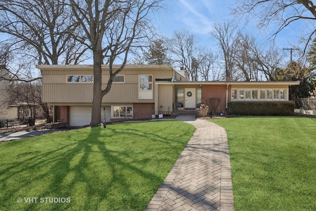 split level home with brick siding, a garage, driveway, and a front lawn