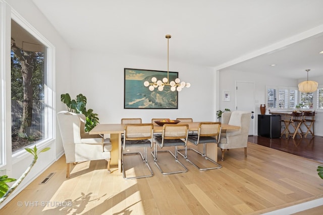 dining room featuring a notable chandelier, visible vents, and wood finished floors