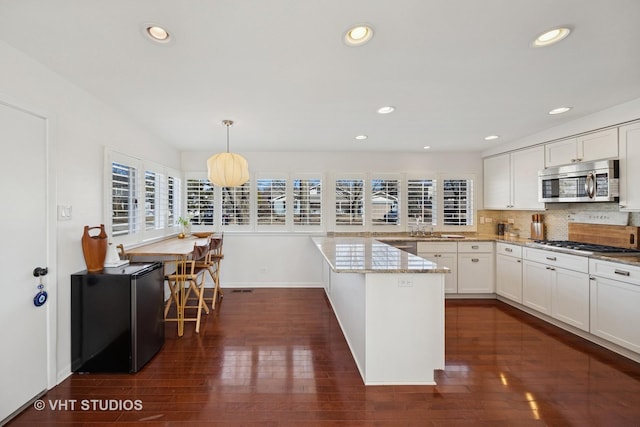 kitchen featuring white cabinetry, dark wood finished floors, tasteful backsplash, and appliances with stainless steel finishes