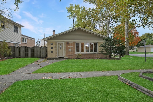 bungalow with a chimney, a gate, a front lawn, and brick siding