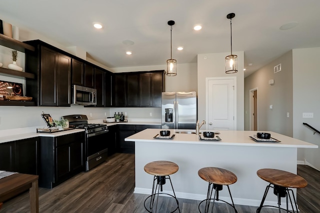 kitchen featuring appliances with stainless steel finishes, dark wood finished floors, a sink, and a kitchen bar