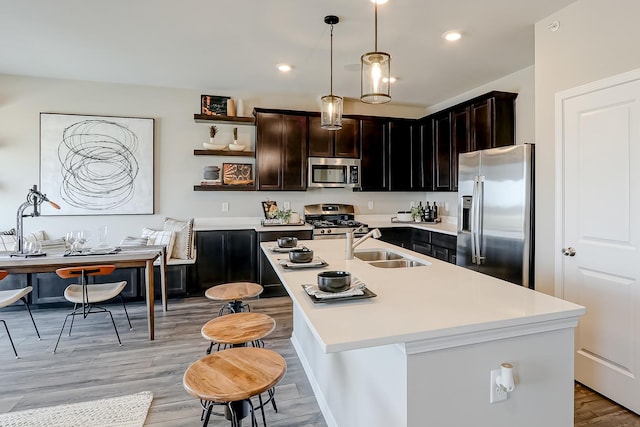 kitchen with stainless steel appliances, light countertops, pendant lighting, a sink, and recessed lighting