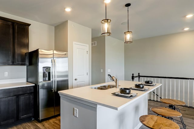 kitchen with stainless steel fridge, visible vents, dark wood-style flooring, light countertops, and a sink