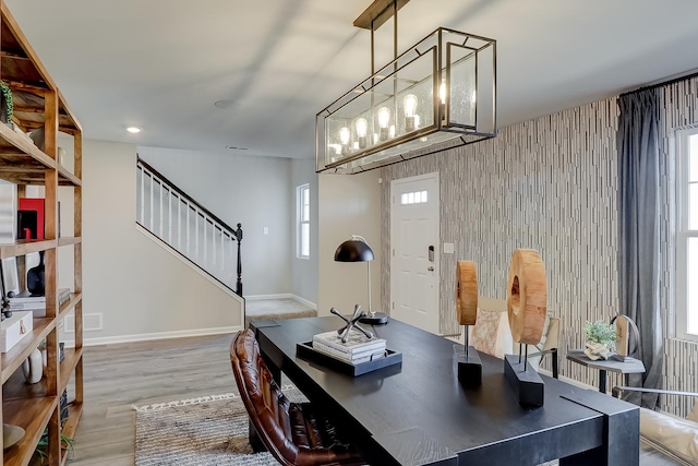 home office with a wealth of natural light, an accent wall, baseboards, and wood finished floors