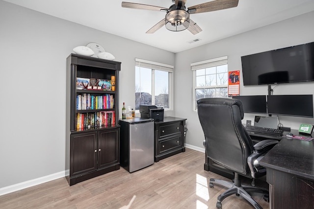 office space with visible vents, light wood-style flooring, baseboards, and ceiling fan