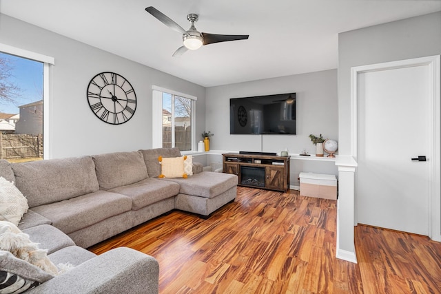 living area featuring baseboards, light wood-style floors, and a ceiling fan