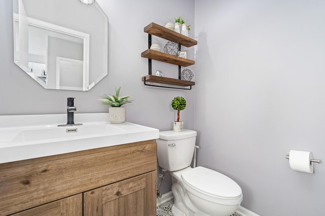 half bath with vanity, toilet, and baseboards