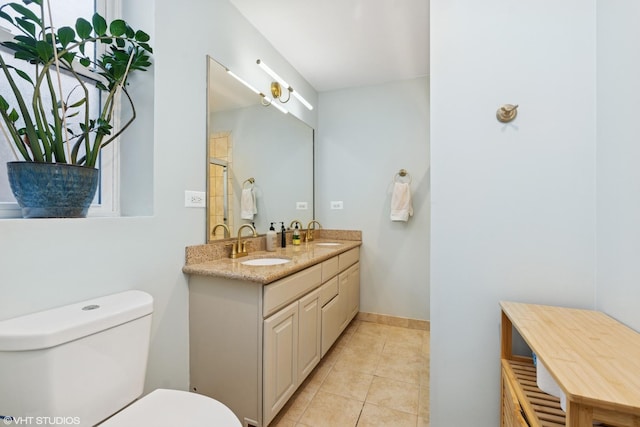 bathroom with tile patterned flooring, double vanity, toilet, and a sink