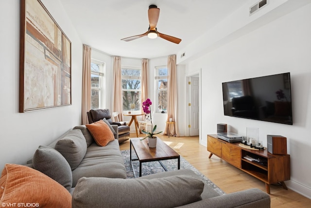 living room with visible vents, baseboards, ceiling fan, and light wood finished floors