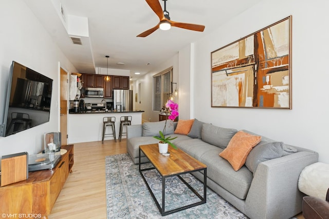 living room featuring visible vents, a ceiling fan, and light wood-type flooring