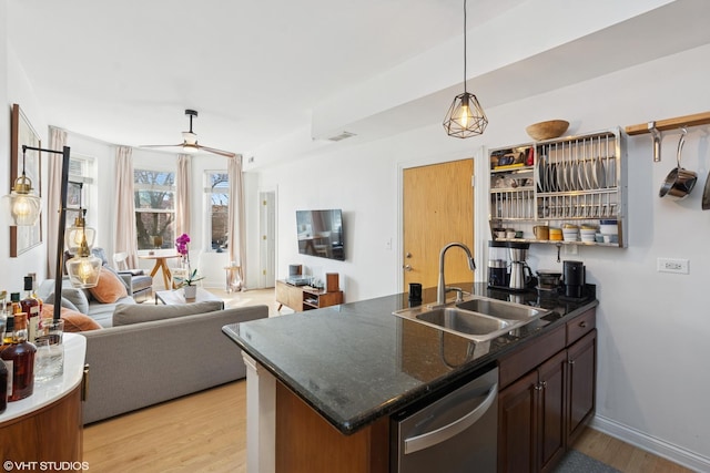 kitchen featuring stainless steel dishwasher, light wood-style flooring, pendant lighting, and a sink