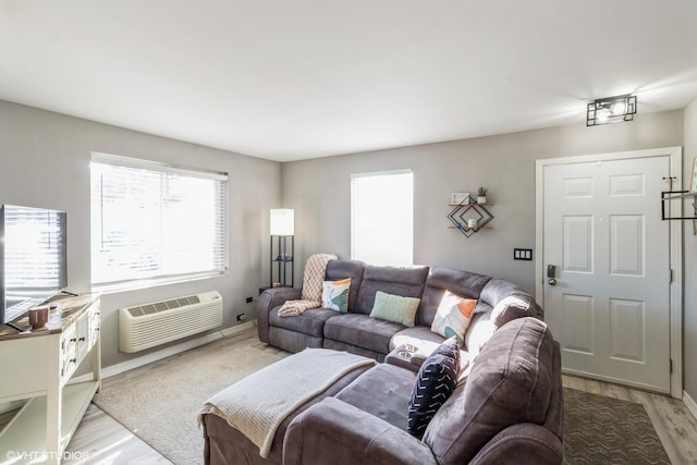 living room featuring light wood-style floors, baseboards, and a wall mounted air conditioner