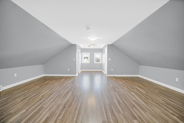 additional living space with baseboards, wood finished floors, and vaulted ceiling