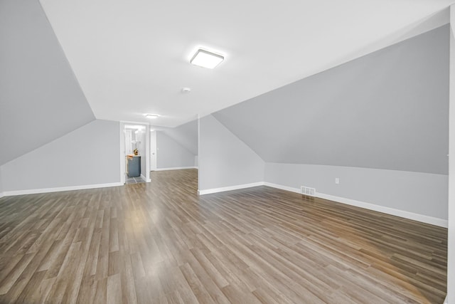 bonus room with vaulted ceiling, visible vents, baseboards, and wood finished floors