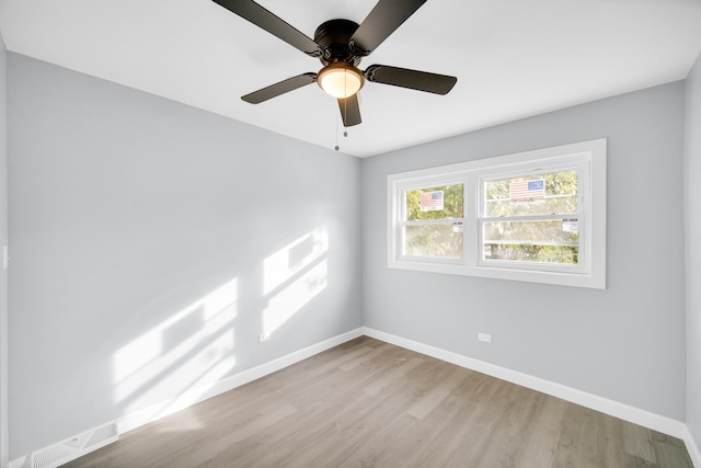 spare room with visible vents, wood finished floors, baseboards, and ceiling fan