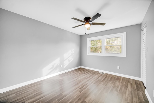 unfurnished room with baseboards, wood finished floors, and a ceiling fan