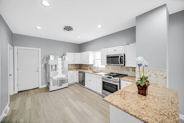 kitchen with white cabinetry, light wood finished floors, appliances with stainless steel finishes, and a sink