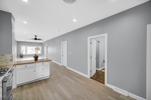 kitchen with gas stove, visible vents, light wood-type flooring, and white cabinetry