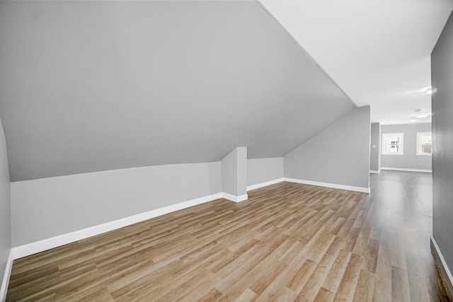 bonus room with baseboards, wood finished floors, and vaulted ceiling