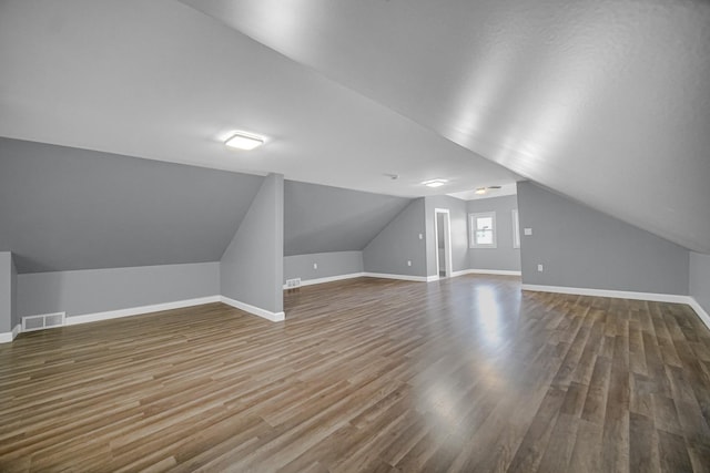 additional living space with visible vents, lofted ceiling, baseboards, and wood finished floors