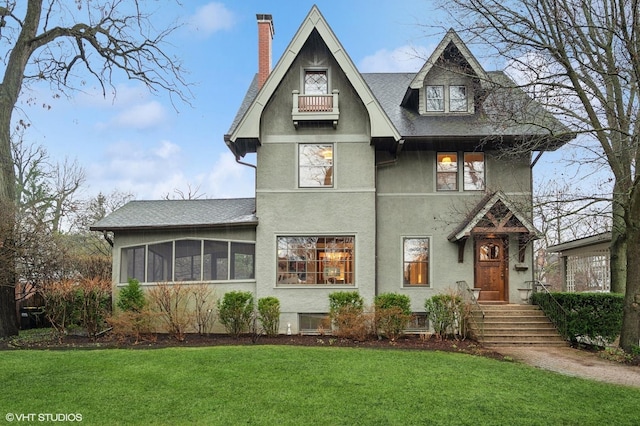 view of front facade with a front lawn, a chimney, stucco siding, and a shingled roof