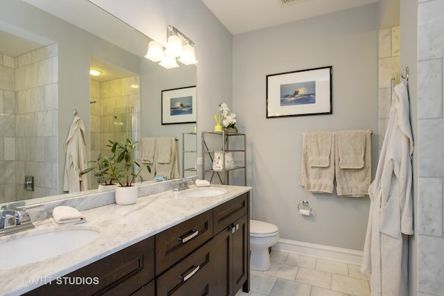 full bath featuring double vanity, baseboards, a tile shower, and a sink