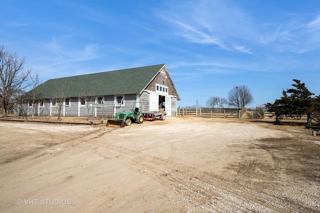 view of front of property with a detached garage, fence, and dirt driveway