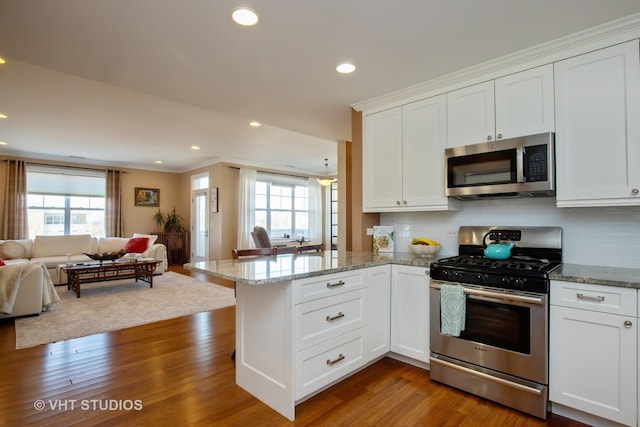 kitchen with a peninsula, plenty of natural light, open floor plan, and appliances with stainless steel finishes