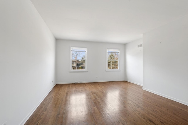 spare room featuring visible vents, baseboards, and wood finished floors