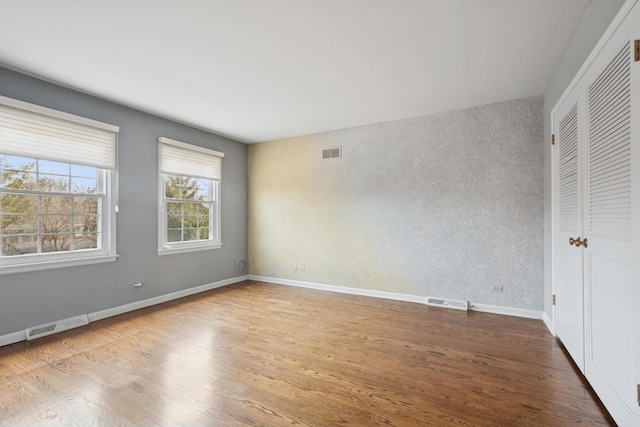 unfurnished bedroom featuring visible vents, baseboards, and wood finished floors