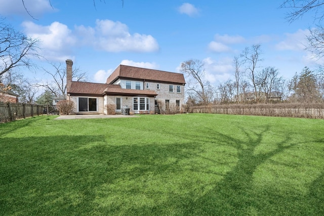 back of property featuring a lawn, fence private yard, a chimney, and a patio area