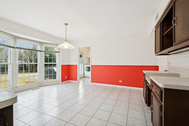 kitchen featuring light tile patterned floors, visible vents, washer / clothes dryer, light countertops, and dark brown cabinetry