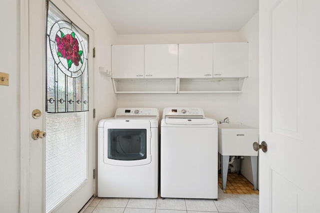 clothes washing area featuring washing machine and clothes dryer, light tile patterned floors, and cabinet space